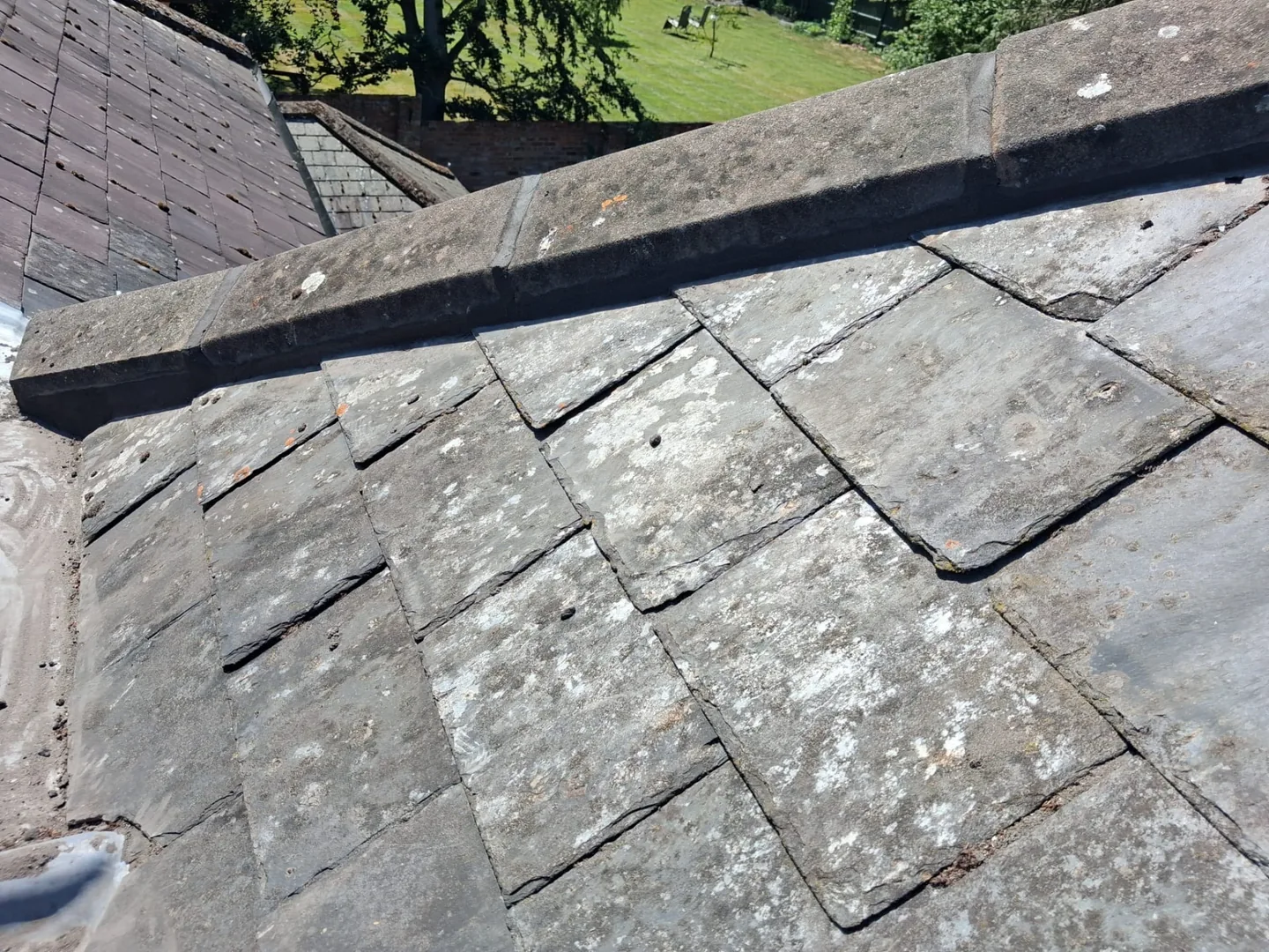 Cracked and weathered slate tiles that need replacing on a pitched roof