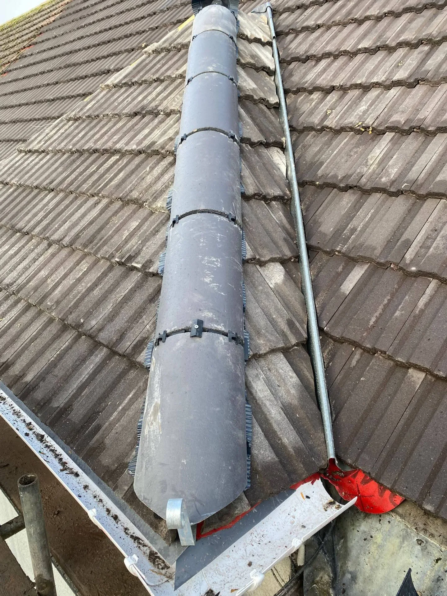 Dry fix ridge system being installed along the ridge line of a tiled roof