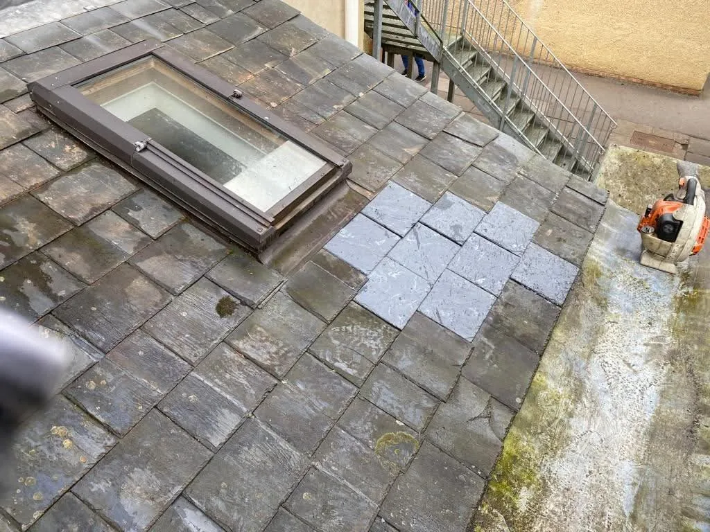 Broken roof tile being replaced with a matching new tile on a pitched roof